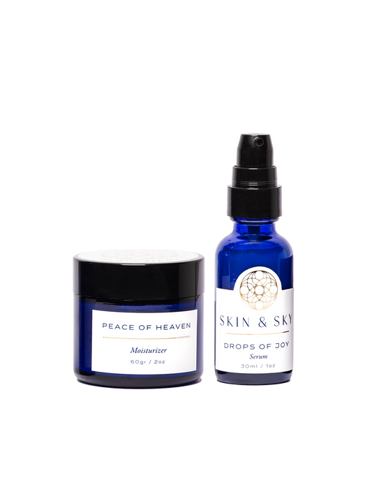 Blissful Set de Skin & Sky que incluye la crema hidratante Peace of Heaven (60g) y el serum Drops of Joy (30ml) en elegantes envases de vidrio azul cobalto con etiquetas blancas, diseñado para restaurar el equilibrio y la luminosidad natural de la piel.