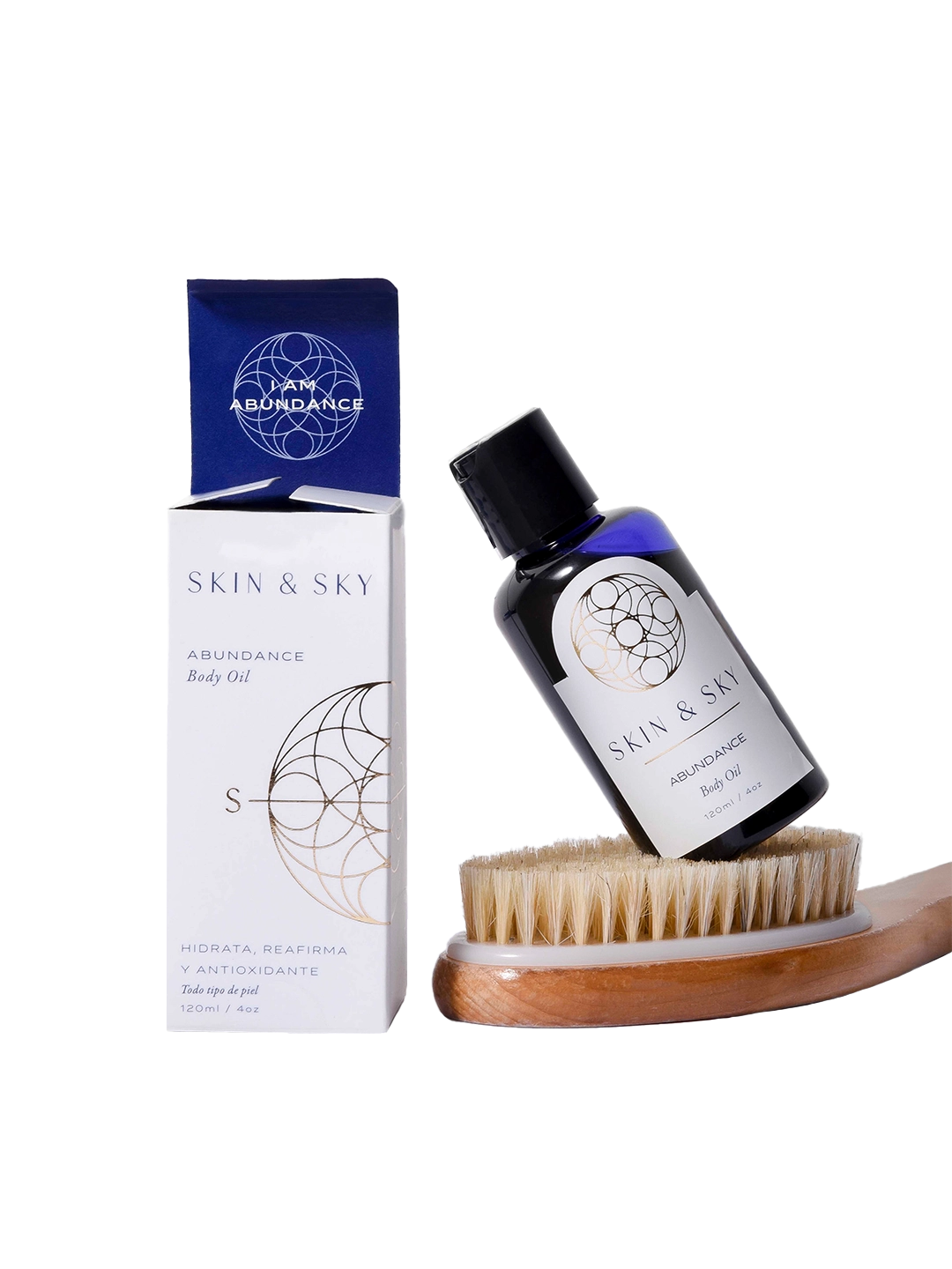 Set Body Duo de Skin & Sky que incluye el aceite corporal Abundance de 120ml apoyado sobre un cepillo de cerdas naturales para exfoliación en seco, junto a su empaque minimalista blanco y azul.