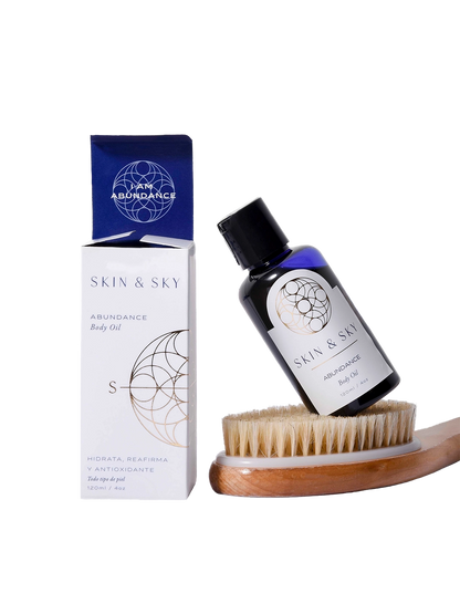 Set Body Duo de Skin & Sky que incluye el aceite corporal Abundance de 120ml apoyado sobre un cepillo de cerdas naturales para exfoliación en seco, junto a su empaque minimalista blanco y azul.