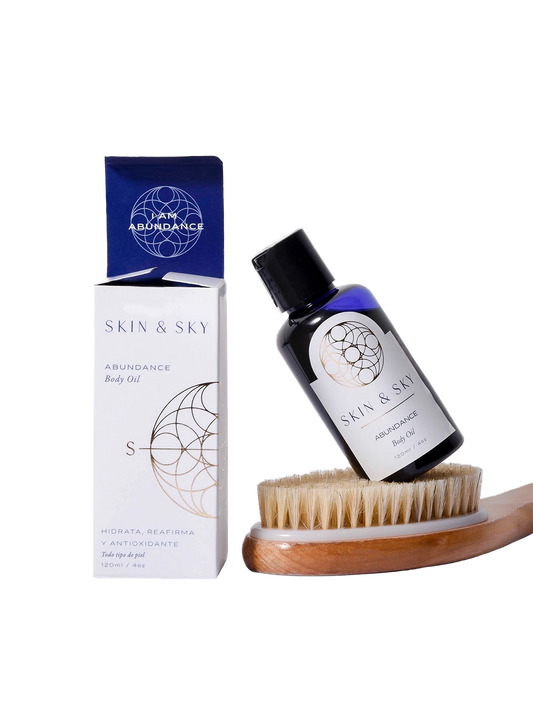 Set Body Duo de Skin & Sky que incluye el aceite corporal Abundance de 120ml apoyado sobre un cepillo de cerdas naturales para exfoliación en seco, junto a su empaque minimalista blanco y azul.