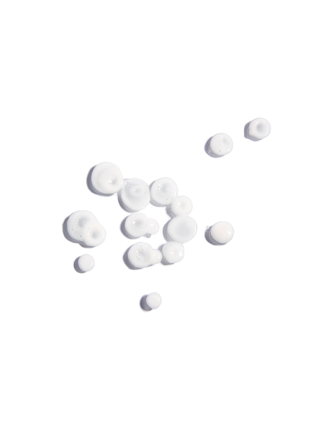 Gotas del suero facial Drops of Joy cayendo del aplicador; una textura líquida, ligera y transparente enriquecida con aceite de chía, romero y albahaca para equilibrar la piel.