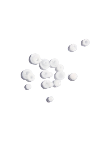 Gotas del suero facial Drops of Joy cayendo del aplicador; una textura líquida, ligera y transparente enriquecida con aceite de chía, romero y albahaca para equilibrar la piel.