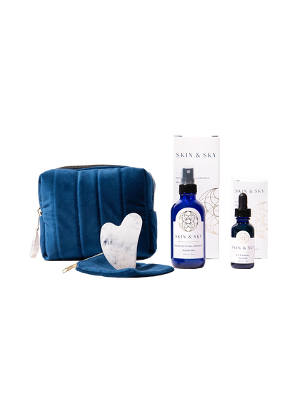 Eternity Set de Skin & Sky: incluye el Eternal Facial Oil (30ml), Rose & Hyaluronic Radiant Mist (120ml), una Gua Sha de cuarzo blanco con su funda protectora y una cosmetiquera de terciopelo azul marino, presentados con sus cajas de empaque minimalistas.