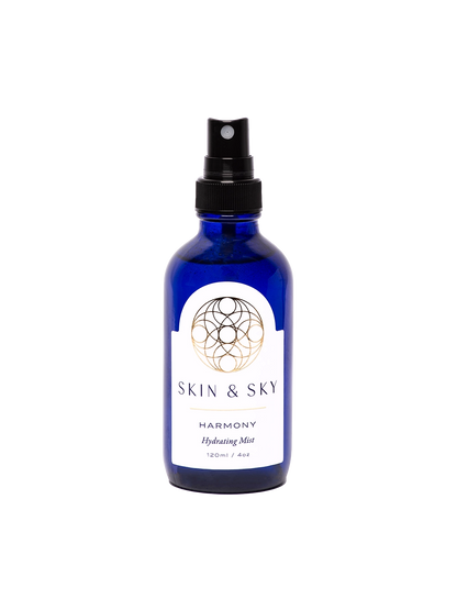 Frasco azul con atomizador negro y etiqueta blanca, bruma facial hidratante y calmante para piel normal, seca y sensible, 120 ml.