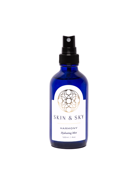 Frasco azul con atomizador negro y etiqueta blanca, bruma facial hidratante y calmante para piel normal, seca y sensible, 120 ml.