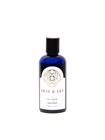 Botella azul de In Love Facial Wash de Skin & Sky, 120 ml / 4 oz. Limpieza facial hidratante y equilibrante con diseño elegante del logotipo doradao en la etiqueta. Limpia, hidrata y nutre la piel con salvia, menta, eucalipto, rosa mosqueta, granada y miel.