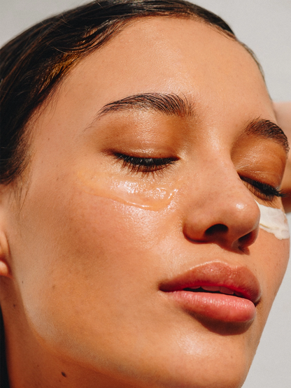 Close-up de una mujer con el gel para ojos Aware aplicado; la textura es cristalina y refrescante, ideal para desinflamar e hidratar la delicada piel del contorno de ojos.