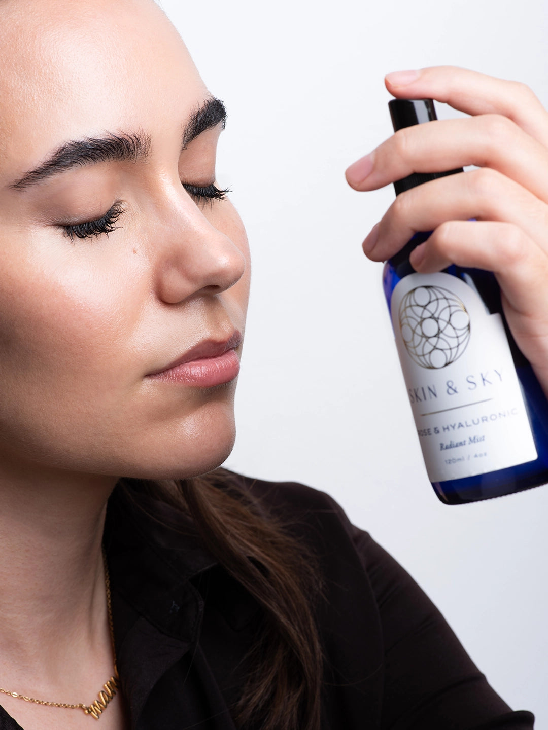 Modelo con ojos cerrados disfrutando de la aplicación de Rose & Hyaluronic Radiant Mist, una bruma facial de rosas y ácido hialurónico que aporta luminosidad y frescura instantánea.