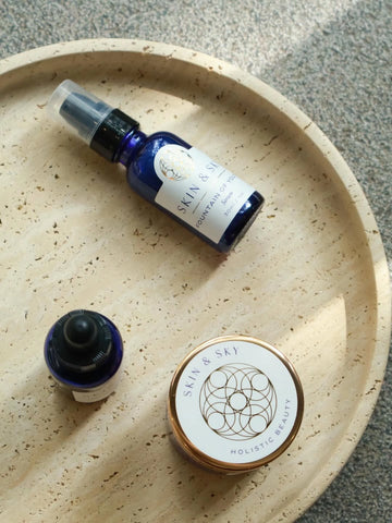 Two bottles and a container with 'Skin & Sky' branding on a beige plate.