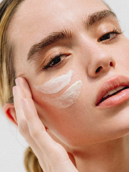 Modelo aplicando Unlimited Moisturizer en la mejilla, destacando su uso nocturno para despertar con una piel radiante, hidratada y con poros minimizados.